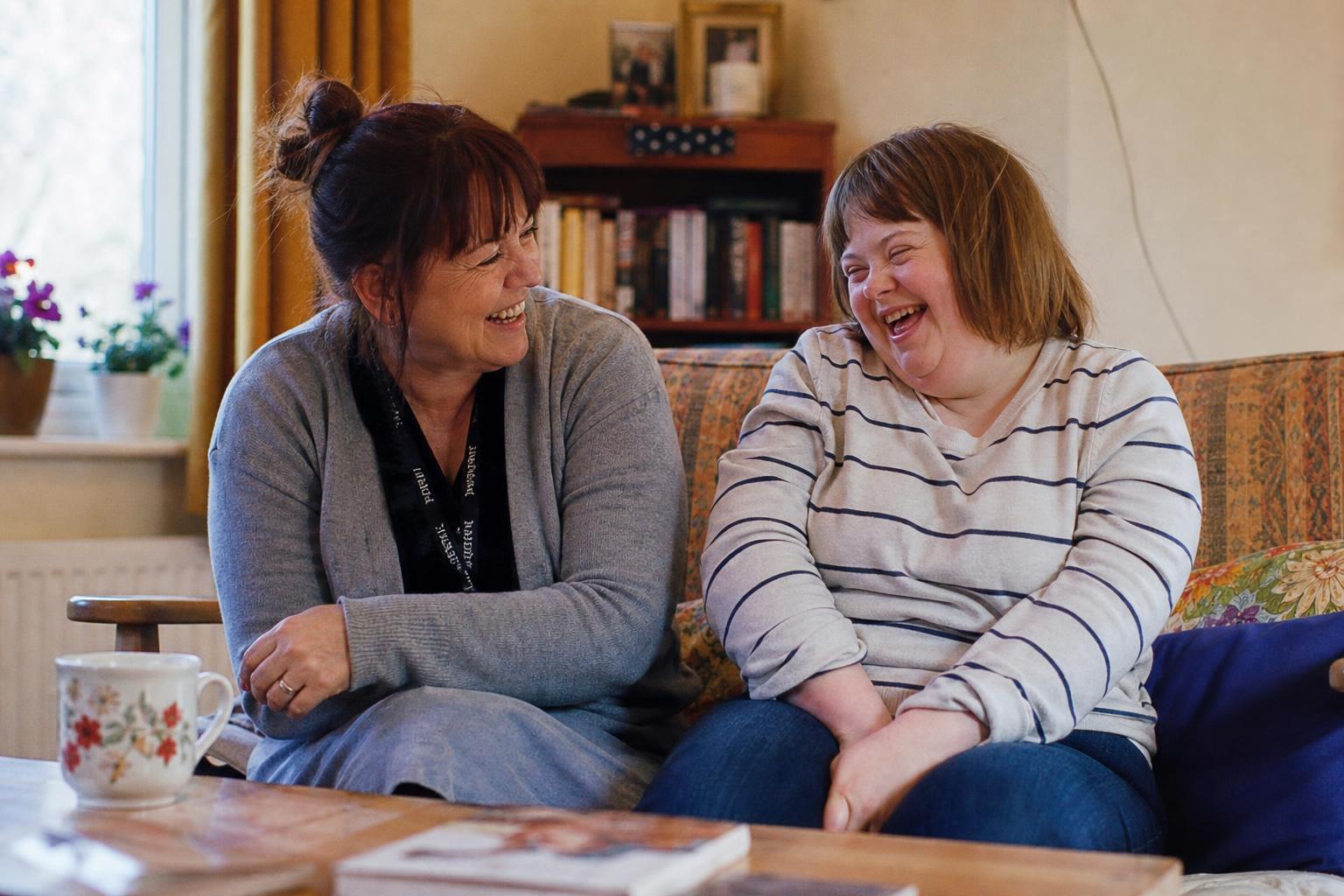Support worker and young adult sharing a moment in a sunny living room